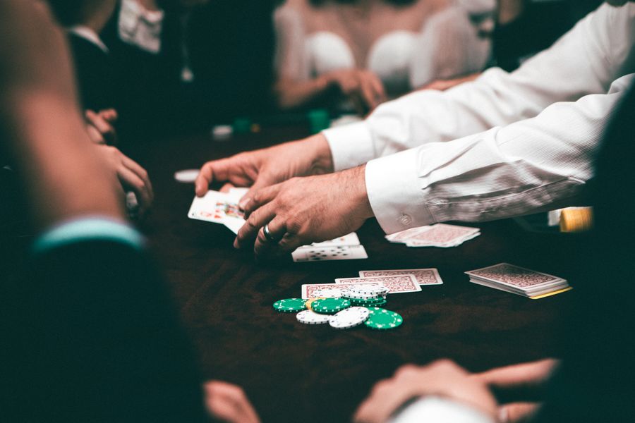 Pemain poker memegang kartu remi di meja dengan tumpukan chip