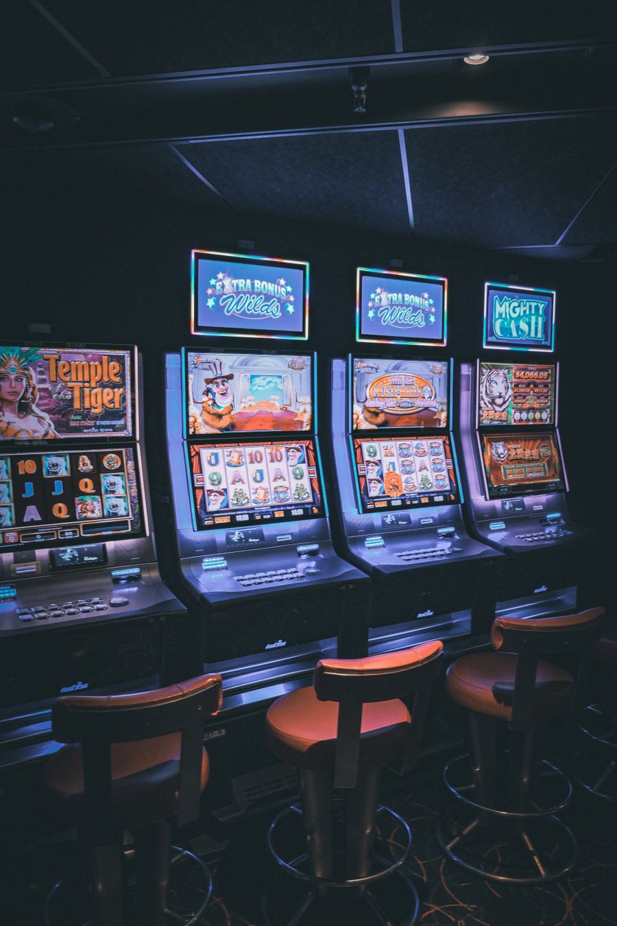Deretan mesin slot dengan layar permainan berwarna-warni di dalam kasino